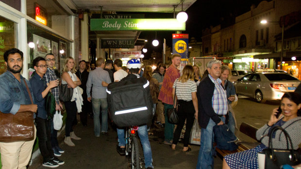 A food delivery cyclist on King Street in Newtown rides on the footpath through a busy bus stop.