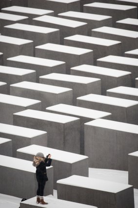 A visitor takes pictures at the snow-covered Holocaust memorial in Berlin.