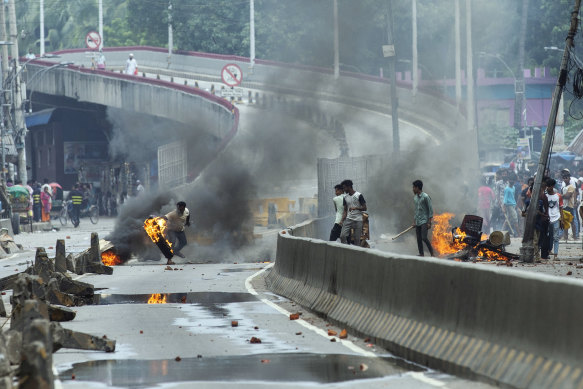 A protester throws a rubber tire on fire during a protest against Sheikh Hasina and her government in Dhaka.