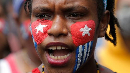 A Papuan student with her face painted with the colours of the separatist 'Morning Star' flag shout slogans during a rally near the presidential palace in Jakarta, Indonesia.