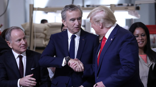 President Donald Trump shakes hands with Bernard Arnault, chief executive of LVMH, during a ribbon cutting ceremony at the Louis Vuitton Workshop Rochambeau in Alvarado, Texas, Thursday, Oct. 17, 2019. At left is Michael Burke, chairman and chief executive officer of of Louis Vuitton - LVMH. (AP Photo/Andrew Harnik)