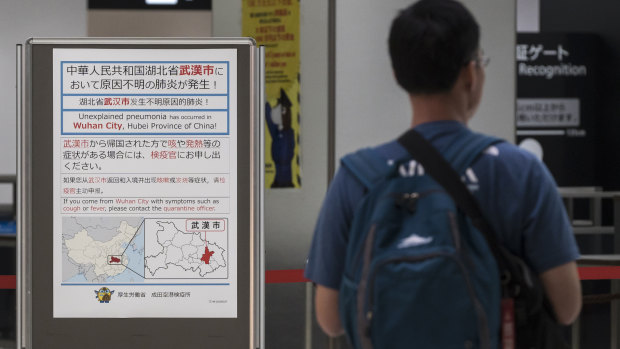 A man walks past a notice for passengers from Wuhan, China, at a quarantine station in Japan's Narita Airport.