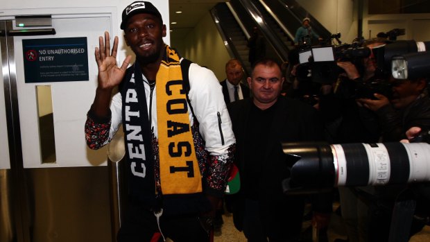 Superstar: Usain Bolt waves to fans as he walks through Sydney Airport.