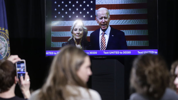 Supporters watch as Joe Biden and wife Jill appear in a video cross during a near-empty New Hampshire rally on primary election night.