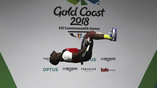 Petit Minkoumba somersaults after a lift during the 94kg weightlifting final at Sunday.
