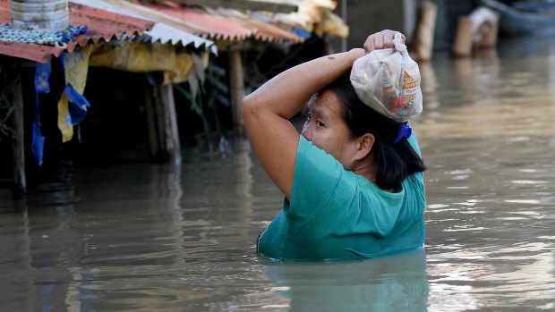 A resident wades through floodwaters after buying basic food items for dinner following flooding brought about by Typhoon Mangkhut which barrelled into northeastern Philippines .