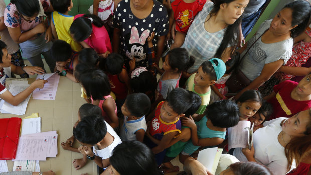 Children and their parents arrive at a health centre in February, in Manila, Philippines, to have their children vaccinated following an outbreak of measles.