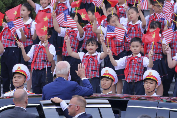 Joe Biden waves to children after a military welcome ceremony at the Presidential Palace in Hanoi, Vietnam, on Sunday.