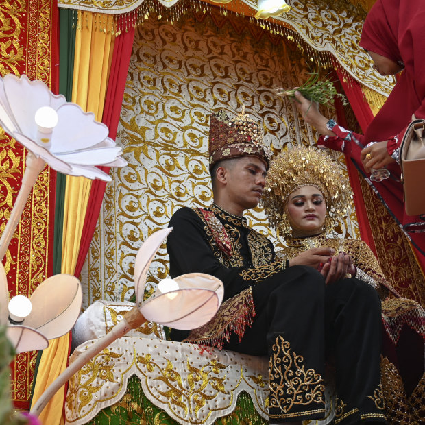 A newly-wedded couple sits on a dais while receiving blessings from family members during a traditional wedding in Banda Aceh, Indonesia.