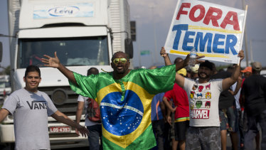 Striking truck drivers protest rising fuel costs and carry a poster reading "Out with Temer" in Duque de Caxias, Brazil.