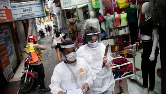 Health workers walk through Brazil's Rocinha slum to test people for COVID-19.