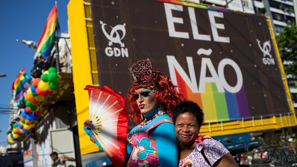 A woman and a drag queen pose for a photo backdropped by a billboard with a message that reads in Portuguese: "Not Him", in reference to presidential candidate Jair Bolsonaro. Bolsonaro has a long history of offensive comments about gays, women and minorities. 