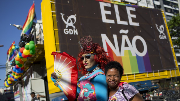 A woman and a drag queen pose for a photo backdropped by a billboard with a message that reads in Portuguese: "Not Him", in reference to presidential candidate Jair Bolsonaro. Bolsonaro has a long history of offensive comments about gays, women and minorities. 