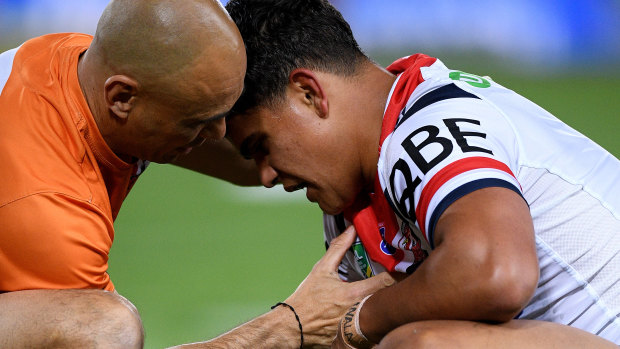 Knock: Latrell Mitchell receives assistance from a trainer during the Roosters' clash with the Eels.