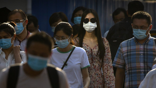 People wearing face masks wait to cross an intersection in Beijing's CBD.