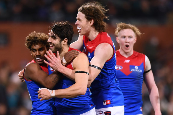 Christian Petracca celebrates one of his three goals with Kysaiah Pickett, who also kicked three goals, and Ben Brown.