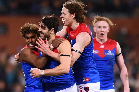 Christian Petracca is mobbed by teammates after a goal.