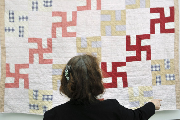 JoAnna Stull of the Greeley History Museum looks at a quilt decorated with swastikas in Greeley, Colorado. The quilt was probably made before 1930, according to the family and the Greeley Museums. 