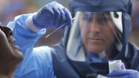 Salt Lake County Health Department public health nurse Lee Cherie Booth performs a coronavirus test outside the Salt Lake County Health Department in Salt Lake City. 