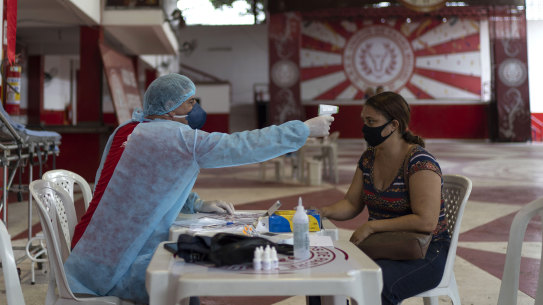 A woman in Rio de Janeiro suspected of having coronavirus has her temperature taken at a clinic. 