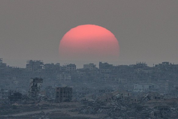 The sun sets behind buildings destroyed during Israeli ground and air operations in the Gaza Strip, as seen from southern Israel.