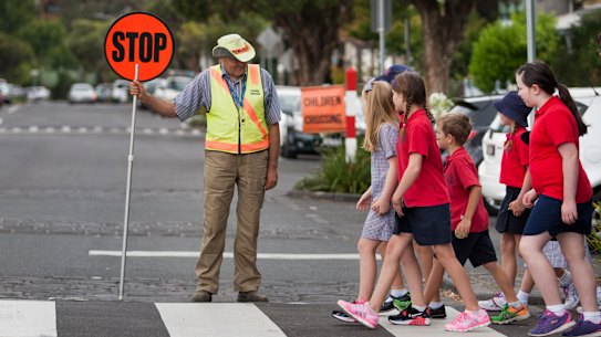 MELBOURNE, AUSTRALIA - JANUARY 27:  Minister for Roads and Road Safety Luke Donnellan (right) and Minister for Education James Merlino announce a change in speed limits in school zones outside Richmond Primary School. Ministers cross Mary St Richmond with Richmond Primary School kids watched by Crossing Supervisor Ian Mc Donald. on January 27, 2015 in Melbourne, Australia.  (Photo by Craig Sillitoe/Fairfax Media)
