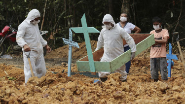 Funeral workers in protective gear prepare a grave at a Manaus cemetery, for a woman who is suspected to have died of COVID-19.