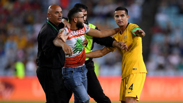 Drama: A pitch invader is restrained by security as he reaches Tim Cahill.