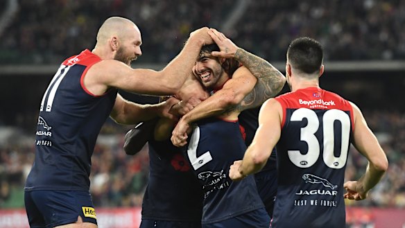 Christian Petracca is congratulated by teammates after kicking a goal.