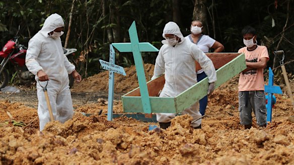 Funeral workers in protective gear prepare a grave at a Manaus cemetery, for a woman who is suspected to have died of COVID-19.