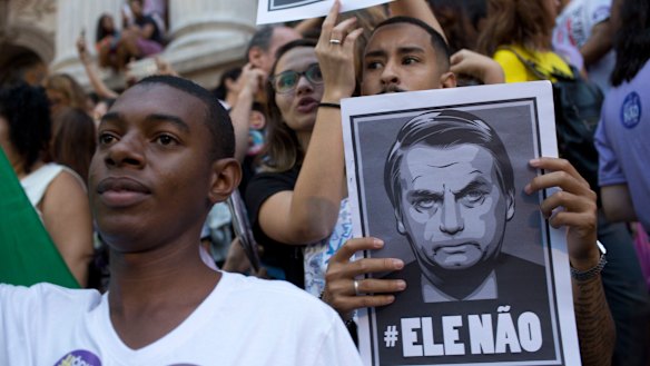 People protest holding signs with a message that reads in Portuguese: "Not him" during a protest against Jair Bolsonaro.