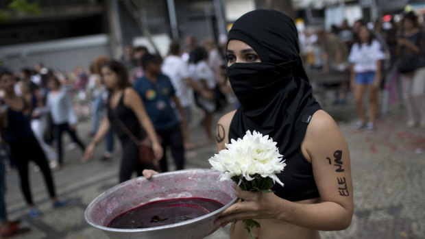 A woman carries a bowl with red ink symbolising the bloodshed that would come if Jair Bolsonaro, the presidential front-runner, were elected, during a protest against Bolsonaro, in Rio de Janiero.