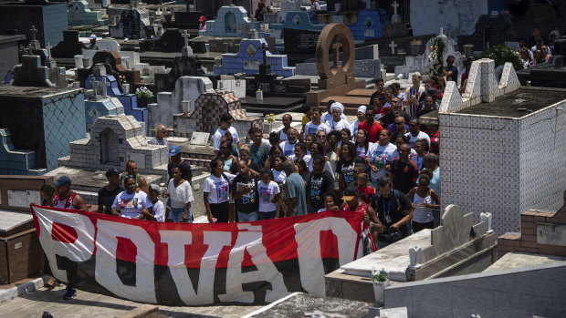 Friends and relatives of Christian Candido carry a banner that reads "People" in Portuguese during his funeral procession in a Rio de Janeiro cemetery.