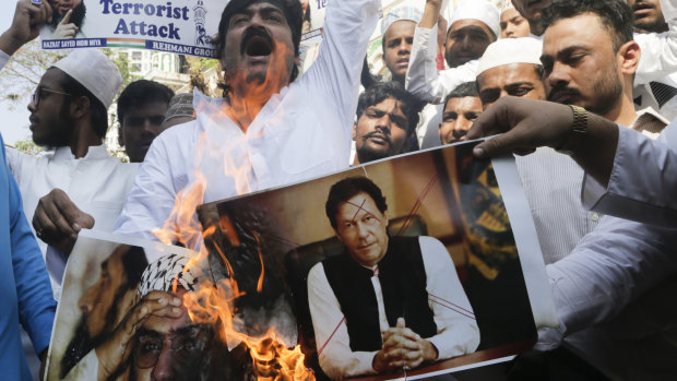 Indian muslims burn posters of Pakistani Prime Minister Imran Khan, centre, and Hafiz Saeed, chief of Pakistani religious group Jamaat-ud-Dawa, during a protest against Thursday's attack on a paramilitary convoy.