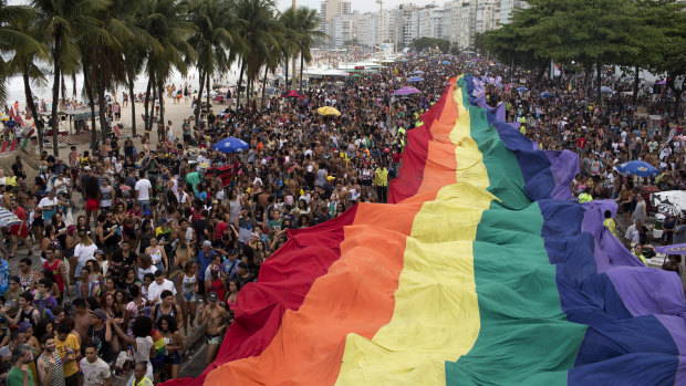People carry a giant rainbow banner in Rio during a Gay Pride parade under the theme "Vote in ideas and not in people," which aims to encourage people to vote for candidates who support gay and human rights.