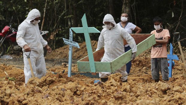 Funeral workers in protective gear prepare a grave at a Manaus cemetery, for a woman who is suspected to have died of COVID-19.