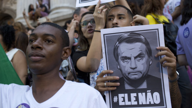 People protest holding signs with a message that reads in Portuguese: "Not him" during a protest against Jair Bolsonaro.