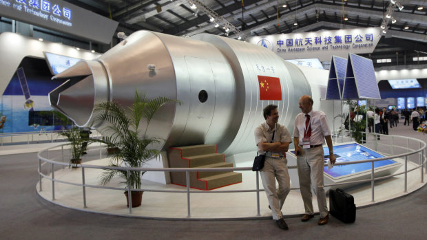  In this 2010 file photo, visitors sit beside a model of China's Tiangong-1 space station at the 8th China International Aviation and Aerospace Exhibition in Zhuhai in southern China's Guangdong Province.
