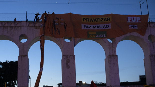 Oil workers hang a banner that reads in Portuguese "Privatisation hurts Brazil" during a protest against layoffs at the oil giant Petrobras in Rio de Janeiro.