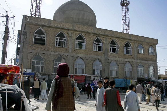 This frame from a video,shows a Taliban fighter standing guard outside the site of a bomb explosion inside a mosque in Mazar-i-Sharif province.
