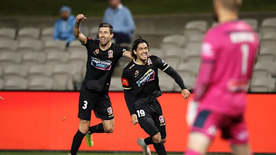 Kosta Petratos celebrates his late, late match-winner with Jets teammate Jason Hoffman as Sydney FC goalkeeper Andrew Redmayne rues an opportunity lost.