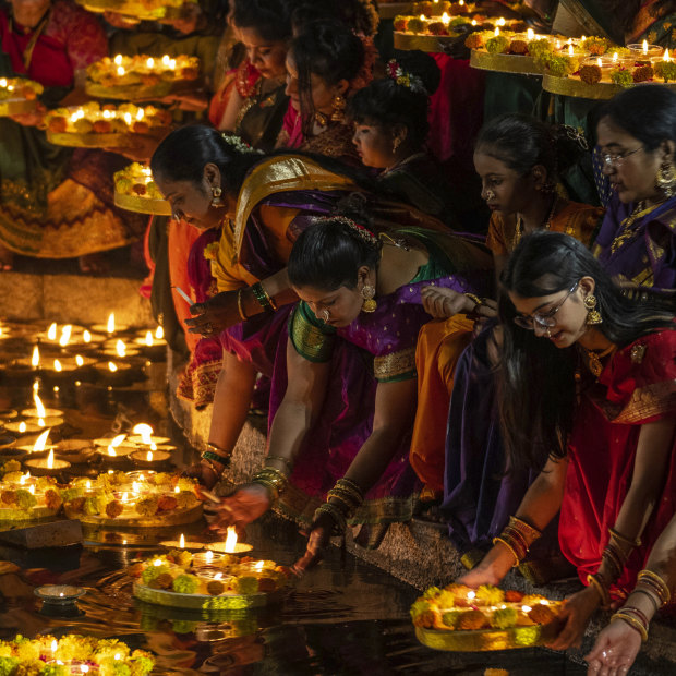Women light oil lamps for Diwali in Mumbai.