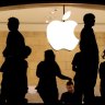 Customers stand beneath an Apple logo at the Apple store in New York.