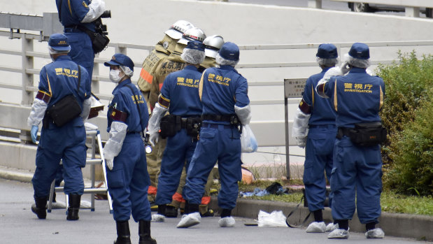 Police and firefighters inspect the scene where a man set himself on fire in Tokyo on Wednesday. 