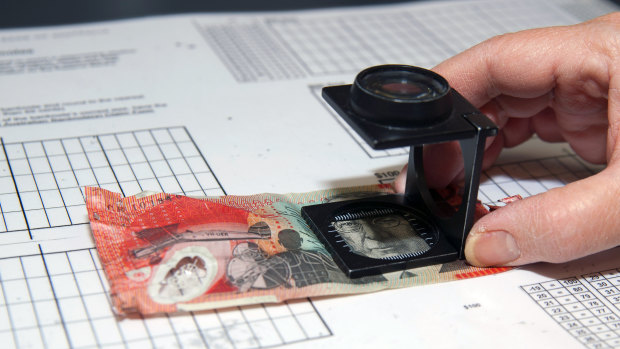 A $20 bill being checked for imperfections. 