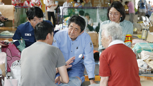 Japanese PM Shinzo Abe listens to an evacuee during a visit to an evacuation center in Kurashiki.