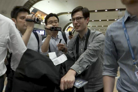 Australian student Alex Sigley walks through journalists as he arrives at the airport in Beijing