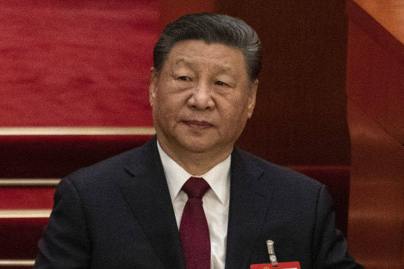 Chinese President Xi Jinping adjusts his jacket as he listens at the opening session of the National People’s Congress.