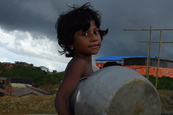 Storm clouds hang overhead as a Rohingya child carried a pot in Kutupalong camp last year.