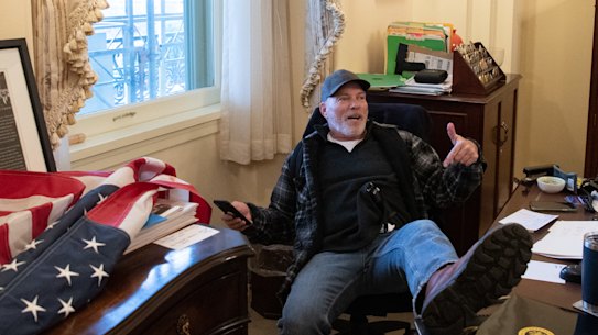 A supporter of US President Donald Trump sits inside the office of US Speaker of the House Nancy Pelosi.